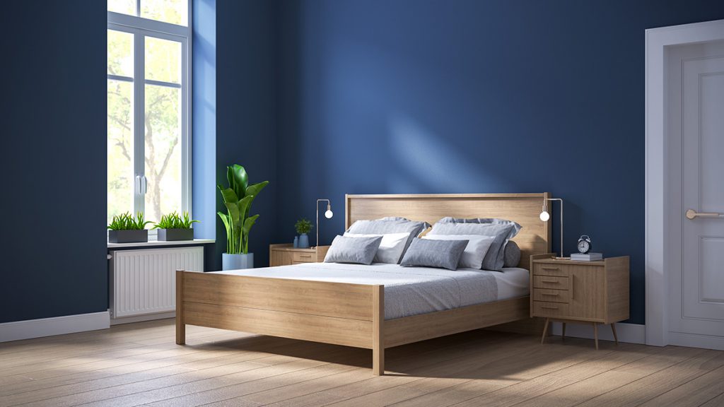 Спалня с дървено легло и шкафчета и синя стена